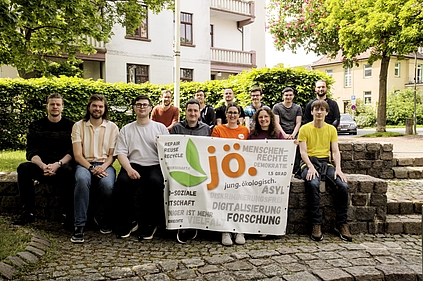 Gruppenbild der teilnehmenden JÖ-Mitglieder der Bundesversammlung 2026. Sie sitzen auf Steinstufen. Die fordere Reihe hält die Fahne der JÖ vor sich.